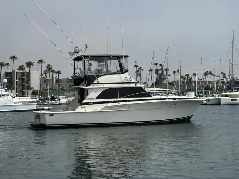 Slide: The Image of 1978 Bertram 46 Convertible yacht docked in a marina with sailboats and palm trees. - 2