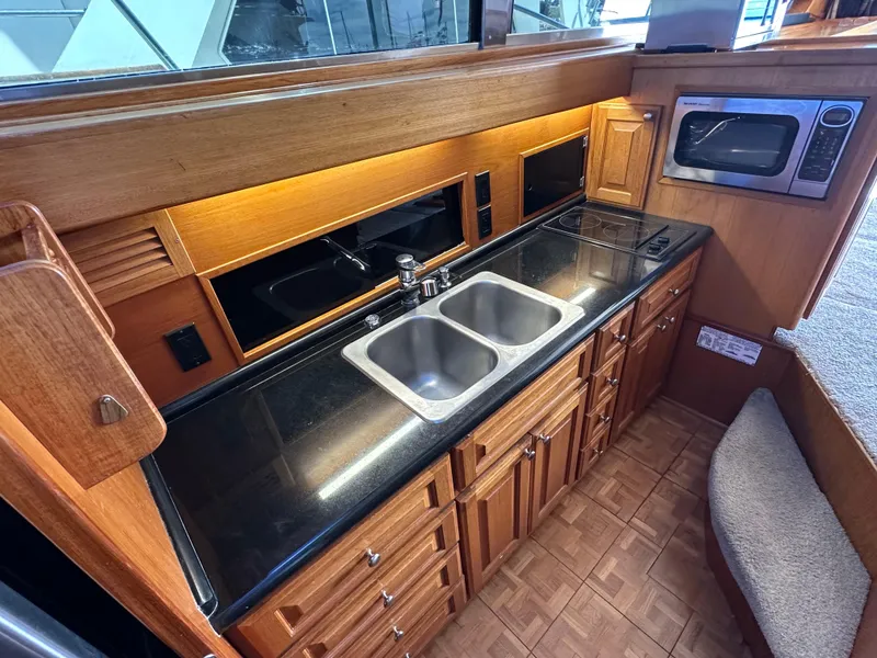 Slide: The Image of 1978 Bertram 46 Convertible yacht kitchen with dual sink, microwave, and wooden cabinetry. - 22
