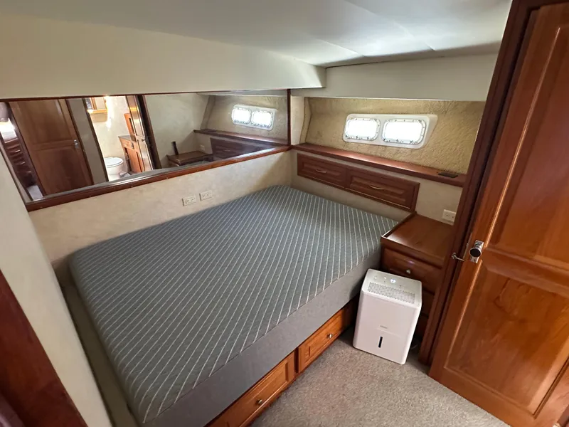 Slide: The Image of 1978 Bertram 46 Convertible cabin with bed, wooden cabinetry, and porthole windows. - 25
