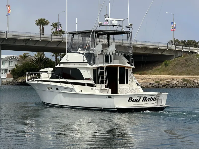 Slide: The Image of 1978 Bertram 46 Convertible yacht cruising under a bridge on a calm waterway. - 6