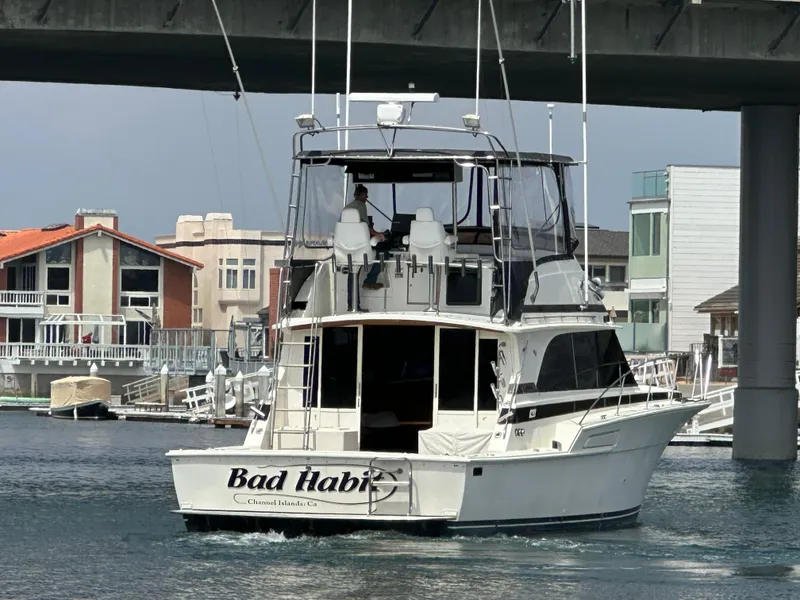 Slide: The Image of 1978 Bertram 46 Convertible yacht named "Bad Habit" cruising under a bridge in a marina. - 7