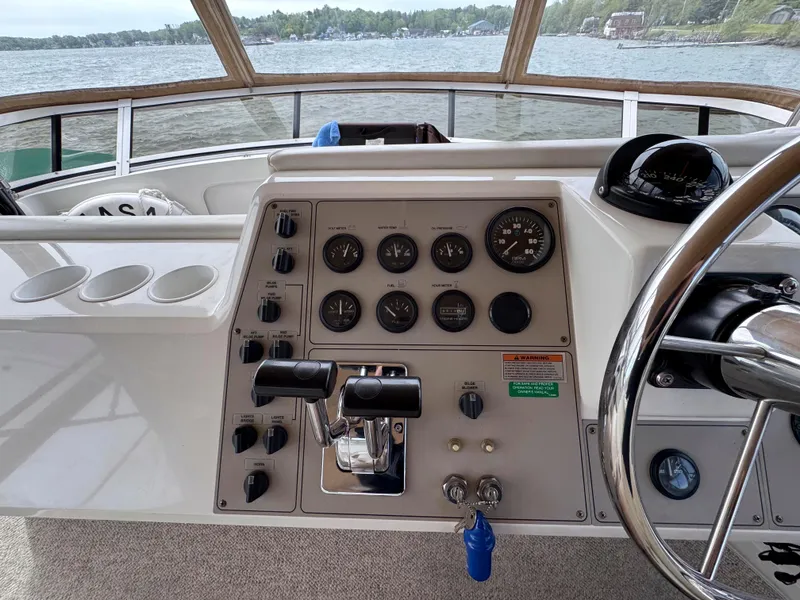 Slide: The Image of 1999 Carver 406 Aft Cabin Motor Yacht helm with controls and gauges, overlooking water. - 17