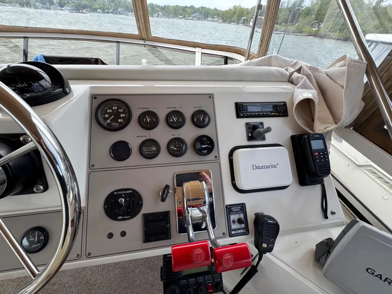 Slide: The Image of 1999 Carver 406 Aft Cabin Motor Yacht helm with gauges and controls, overlooking serene water. - 18