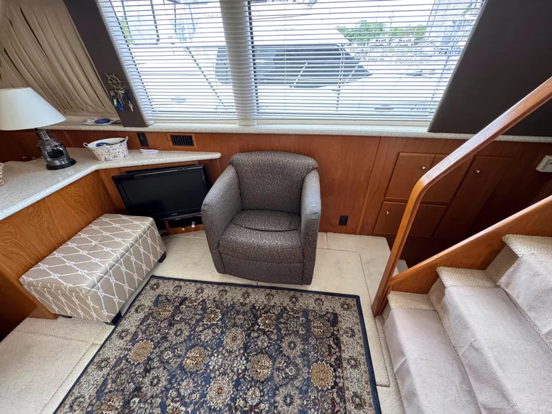 Slide: The Image of 1999 Carver 406 Aft Cabin Motor Yacht interior with chair, ottoman, and patterned rug. - 24