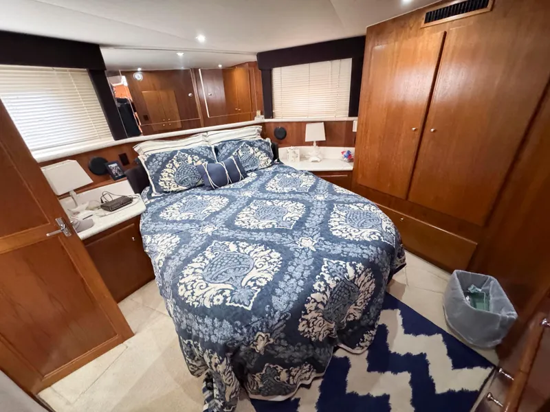 Slide: The Image of 1999 Carver 406 Aft Cabin Motor Yacht bedroom with patterned bedding and wooden cabinetry. - 32