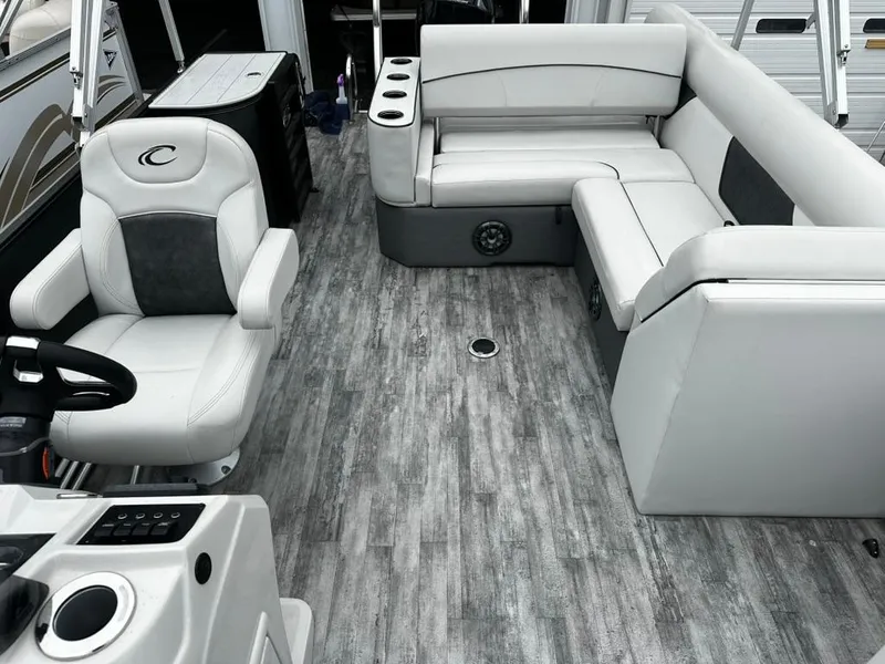 Slide: The Image of 2021 Crest Classic LX 240 SLS boat interior with gray seating and wood-style flooring. - 2