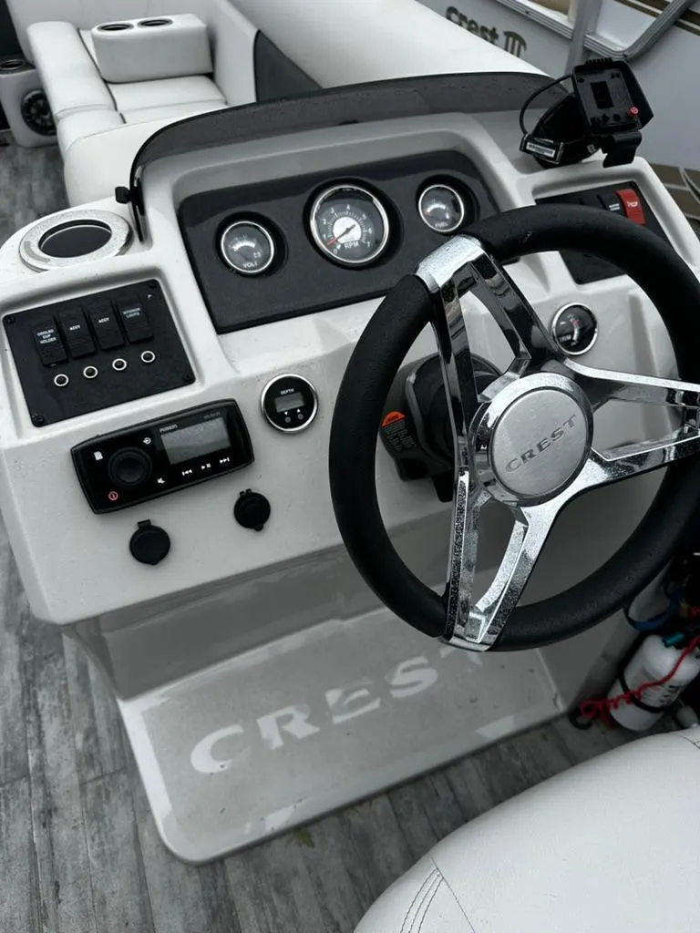 Slide: The Image of 2021 Crest Classic LX 240 SLS boat dashboard with steering wheel and control panel. - 4