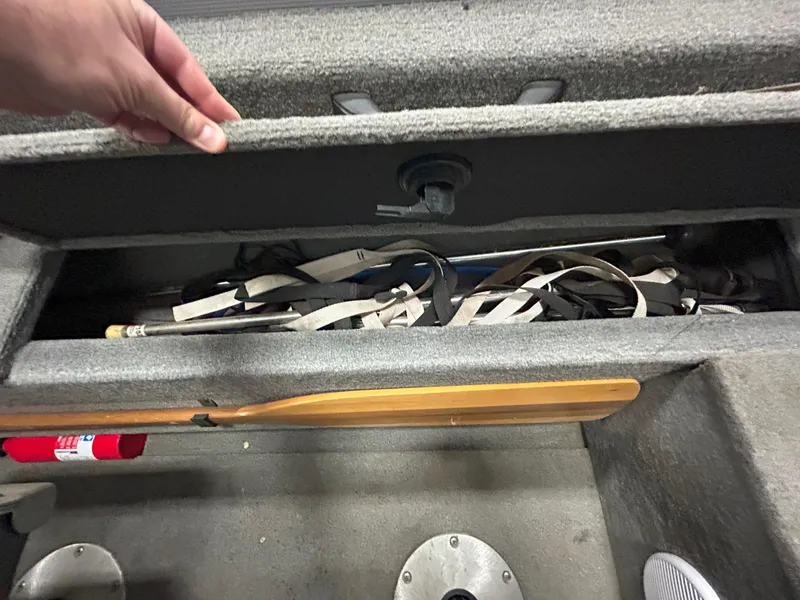Slide: The Image of Storage compartment in a 2005 Tracker Targa 17 SC boat with various items and a paddle. - 13