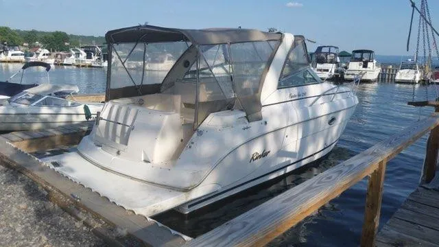 Slide: The Image of 2004 Rinker Fiesta Vee 290 boat docked at a marina with other vessels. - 2