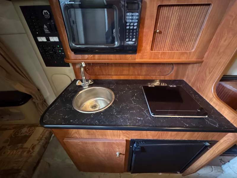 Slide: The Image of 2004 Rinker Fiesta Vee 290 boat kitchenette with sink, microwave, and stove. - 20