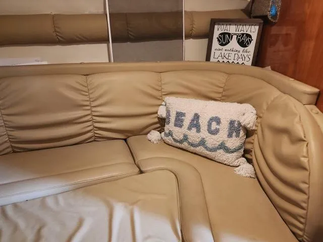 Slide: The Image of 2004 Rinker Fiesta Vee 290 interior with beige seating and a "Beach" pillow. - 23