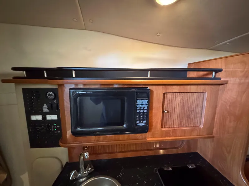 Slide: The Image of 2004 Rinker Fiesta Vee 290 interior kitchen with microwave and wooden cabinetry. - 28