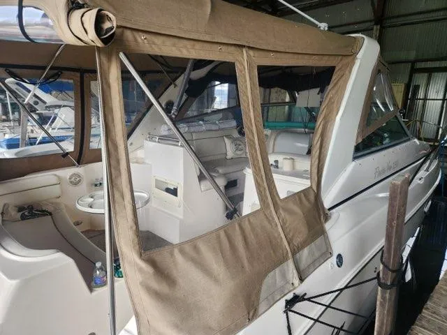 Slide: The Image of 2004 Rinker Fiesta Vee 290 boat with tan canvas cover in a marina setting. - 7