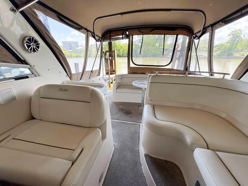 Slide: The Image of 2004 Rinker Fiesta Vee 290 boat interior with beige seating and large windows. - 8
