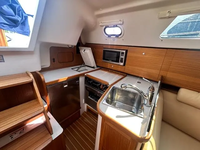 Slide: The Image of Interior of 2015 Catalina 315 sailboat kitchen with wood finish and modern appliances. - 11
