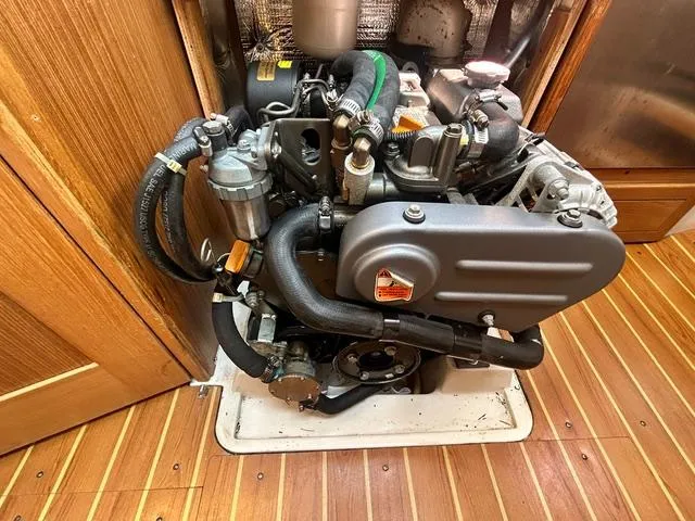 Slide: The Image of Engine of a 2015 Catalina 315 sailboat, showcasing detailed components and wooden flooring. - 14