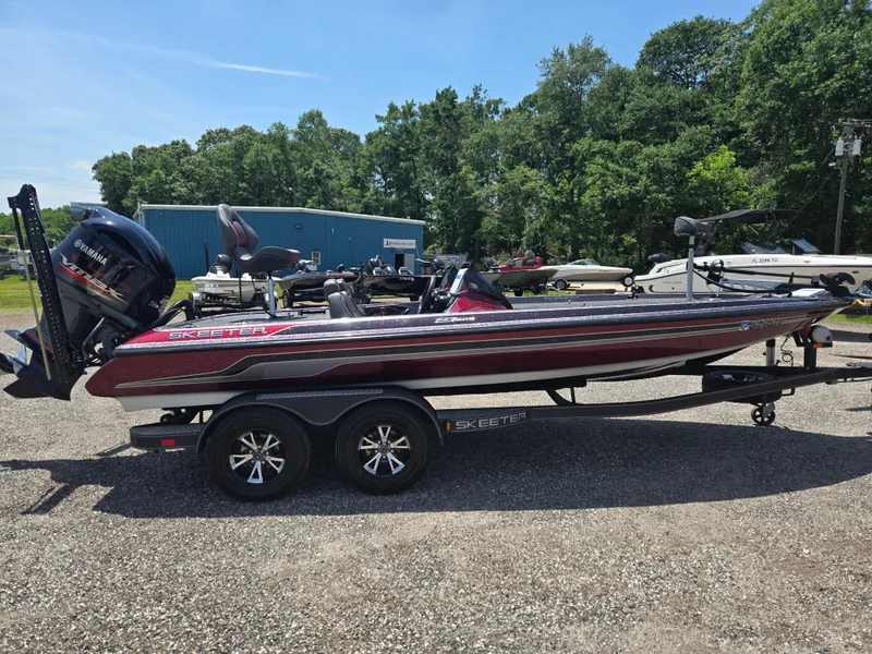 Slide: The Image of 2018 Skeeter ZX 250 boat on trailer, parked outdoors, surrounded by trees and other boats. - 3