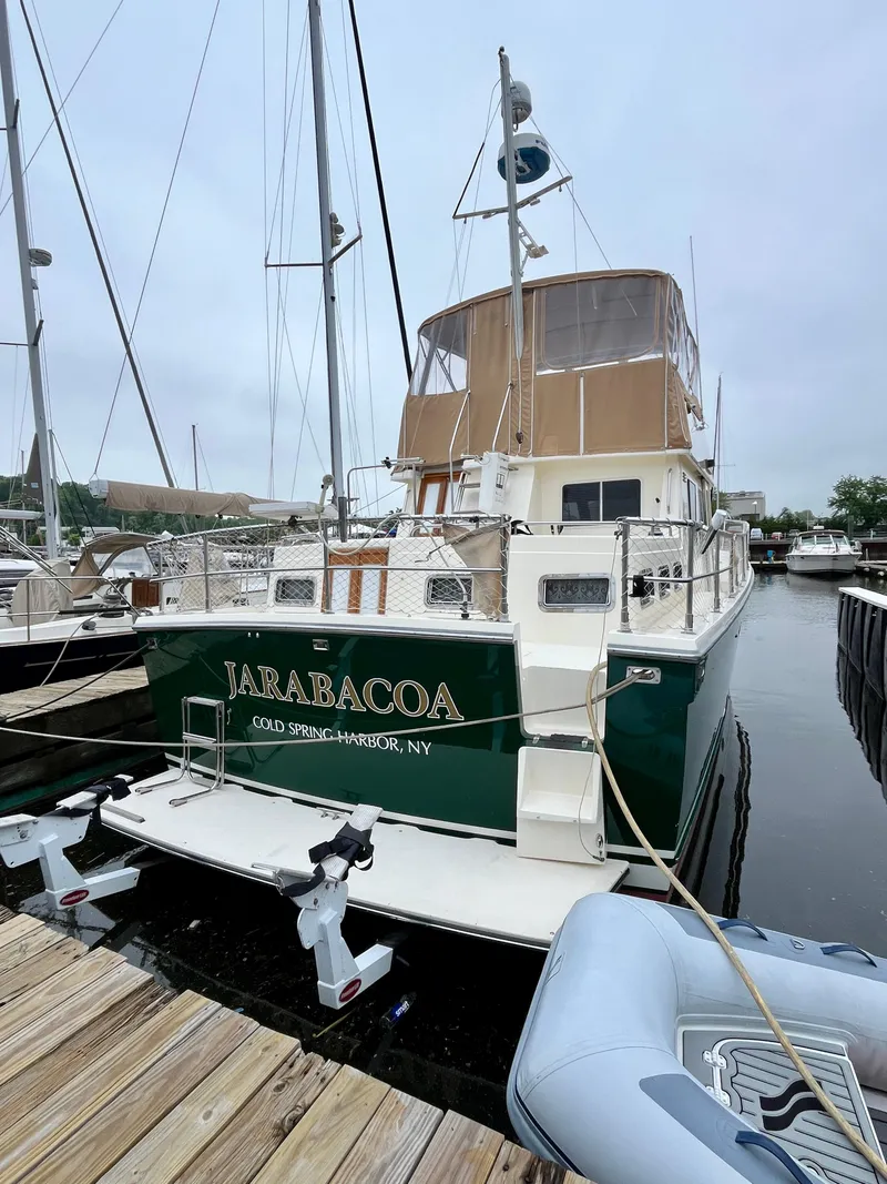 Slide: The Image of 1996 Sabreline 43 Motoryacht docked, featuring a green hull and tan canopy. - 2