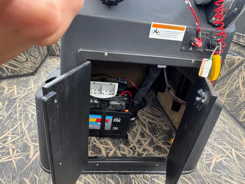 Slide: The Image of 2016 Crestliner 2000 Bay boat battery compartment with open door and visible wiring. - 15