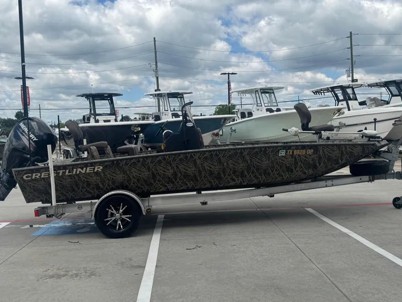 Slide: The Image of 2016 Crestliner 2000 Bay boat with camouflage design on a trailer, parked outdoors. - 22