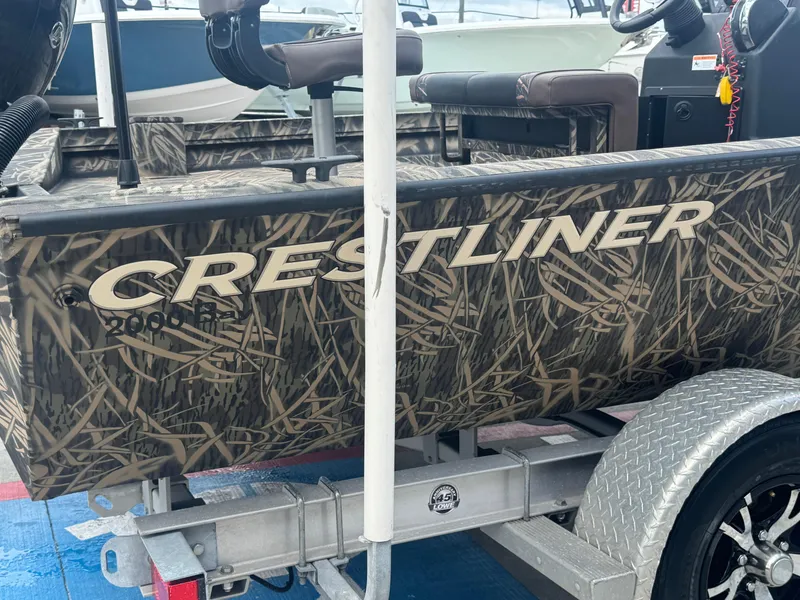 Slide: The Image of 2016 Crestliner 2000 Bay boat with camouflage design on a trailer. - 5