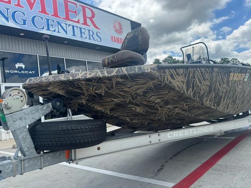 Slide: The Image of 2016 Crestliner 2000 Bay boat with camouflage design on a trailer outside a boating center. - 8