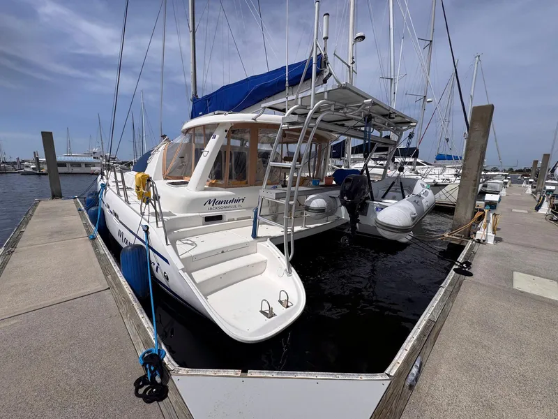 Slide: The Image of 2007 Leopard 43 catamaran docked at marina, featuring blue canopy and inflatable dinghy. - 5