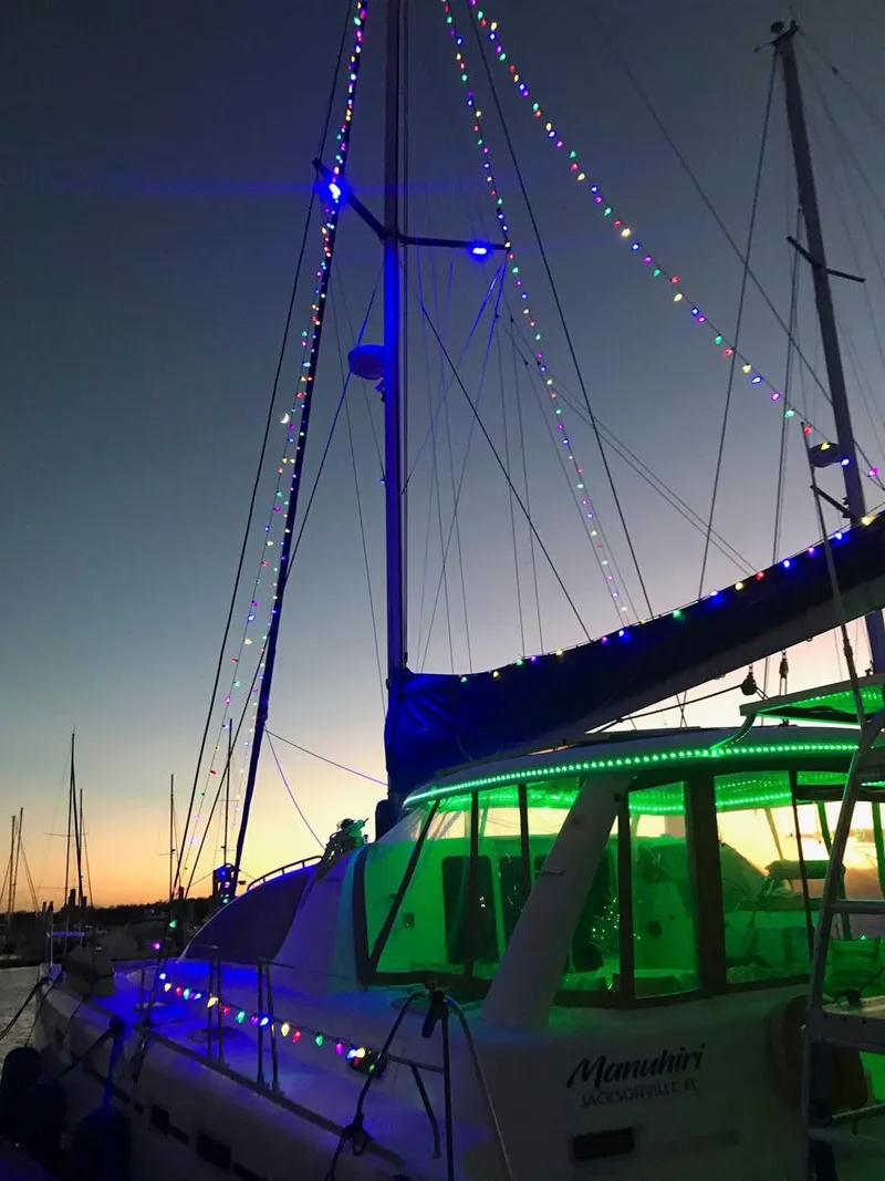 Slide: The Image of Sailboat Leopard 43, 2007 model, adorned with colorful lights at sunset. - 9
