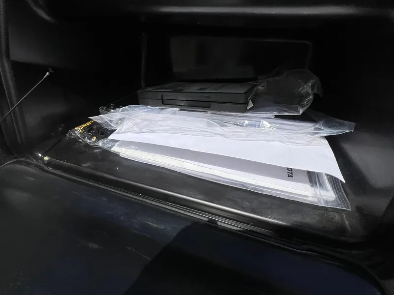 Slide: The Image of Glove compartment with documents and a case in a 2007 Lund 1800 Pro-V SE boat. - 26