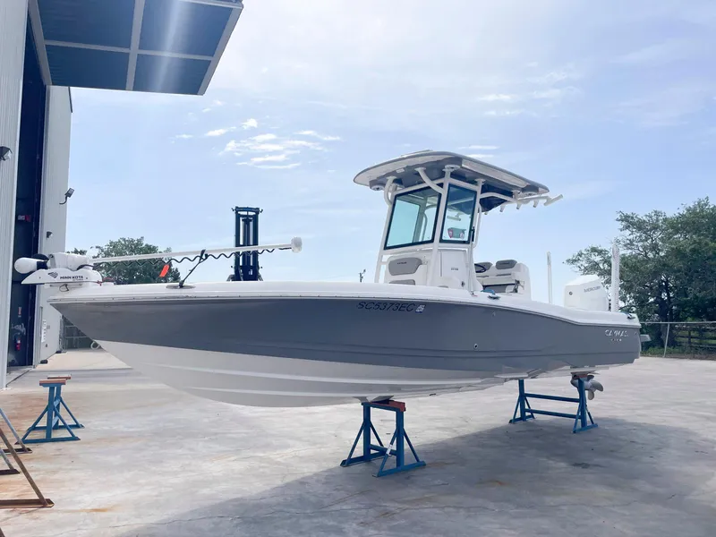 Slide: The Image of 2023 Caymas 26 HB boat on stands, displayed outdoors near a building. - 0