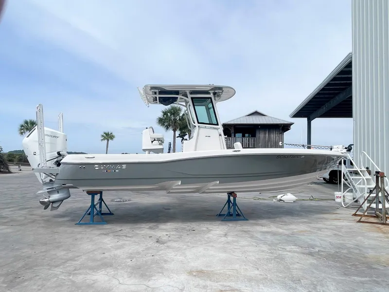 Slide: The Image of 2023 Caymas 26 HB boat on stands, outdoor setting, clear sky background. - 1