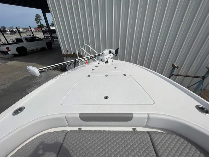 Slide: The Image of 2023 Caymas 26 HB boat bow with trolling motor, docked near a metal building. - 10