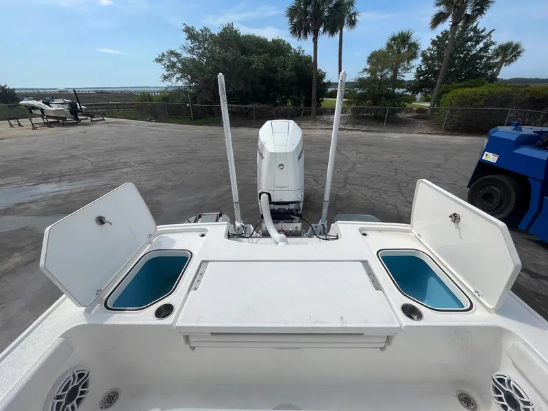 Slide: The Image of 2023 Caymas 26 HB boat with open storage compartments and outboard motor, docked outdoors. - 6