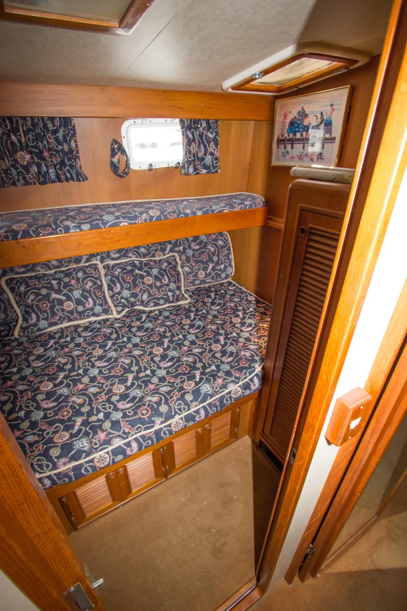Slide: The Image of 1992 Offshore Yachts Sedan cabin with bunk beds, floral bedding, and wooden interior. - 16