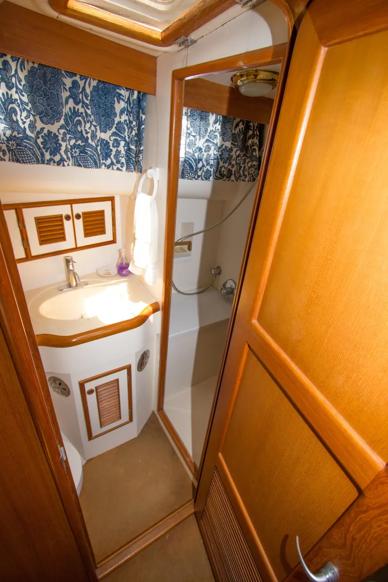 Slide: The Image of 1992 Offshore Yachts Sedan bathroom with wooden cabinetry and compact shower. - 17