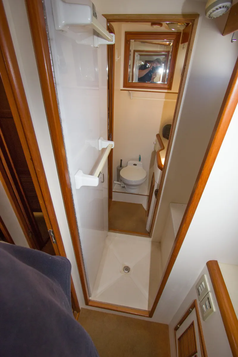 Slide: The Image of 1992 Offshore Yachts Sedan bathroom with shower, toilet, and wooden accents. - 18