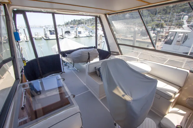 Slide: The Image of 1992 Offshore Yachts Sedan interior with marina view, featuring covered seating and table. - 21
