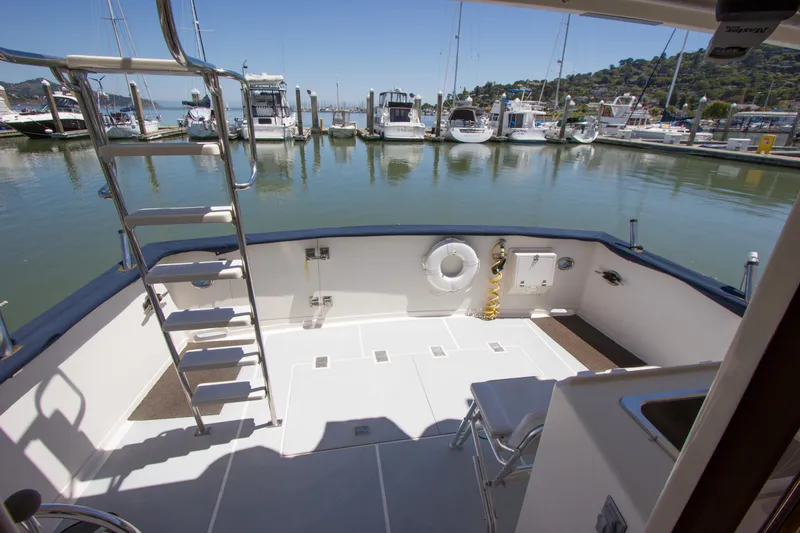 Slide: The Image of 1992 Offshore Yachts Sedan deck with marina view, featuring ladder and seating area. - 31