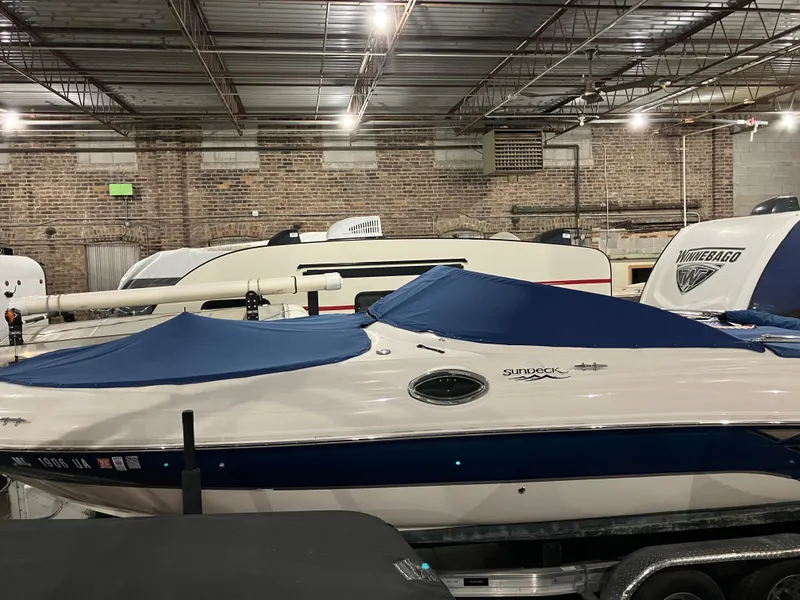 Slide: The Image of 2004 Sea Ray 240 Sundeck boat with blue cover in indoor storage facility. - 2