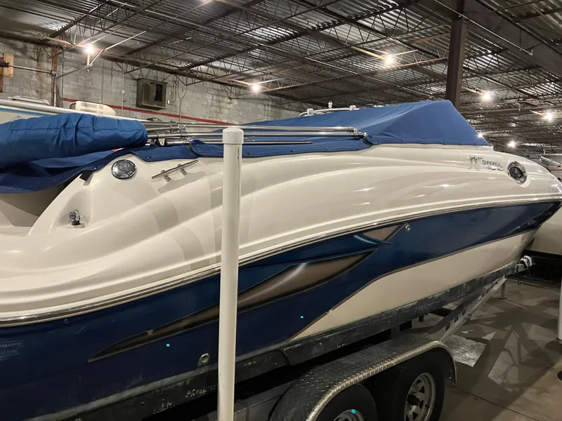 Slide: The Image of 2004 Sea Ray 240 Sundeck boat in storage, blue and white exterior, covered. - 4