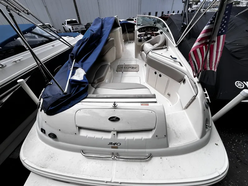 Slide: The Image of 2004 Sea Ray 240 Sundeck boat with American flag, docked and partially covered. - 6