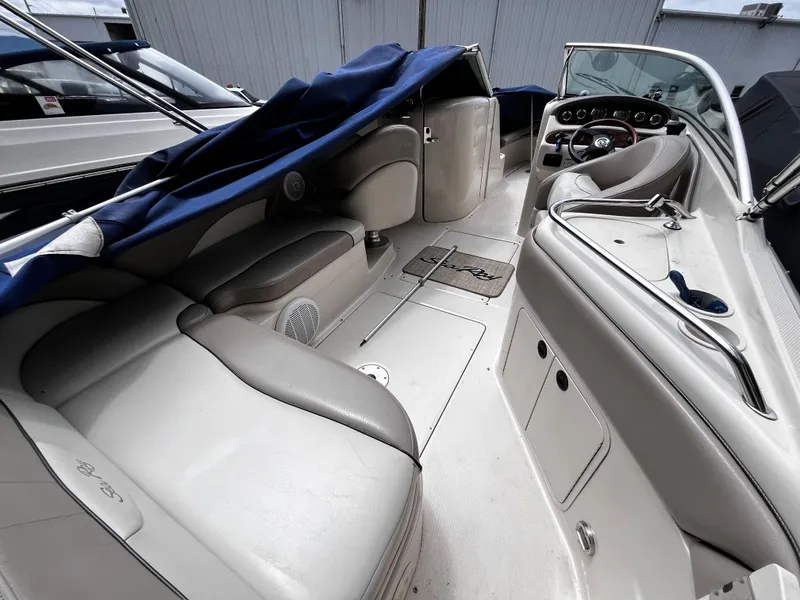 Slide: The Image of 2004 Sea Ray 240 Sundeck interior with seating and dashboard, covered in blue tarp. - 7