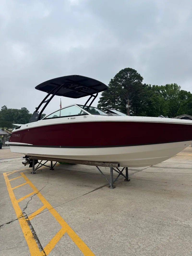 Slide: The Image of 2023 Cobalt R4 boat with red hull on a stand, overcast sky background. - 1
