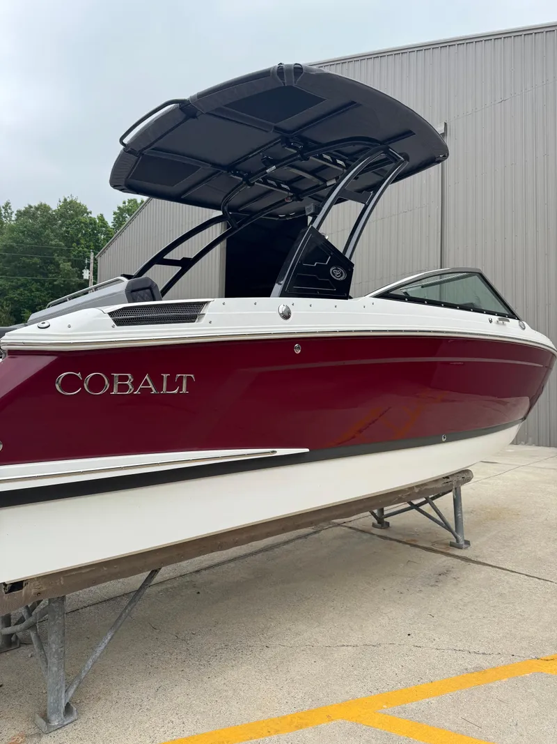 Slide: The Image of 2023 Cobalt R4 boat with maroon hull and black canopy, displayed outdoors. - 4