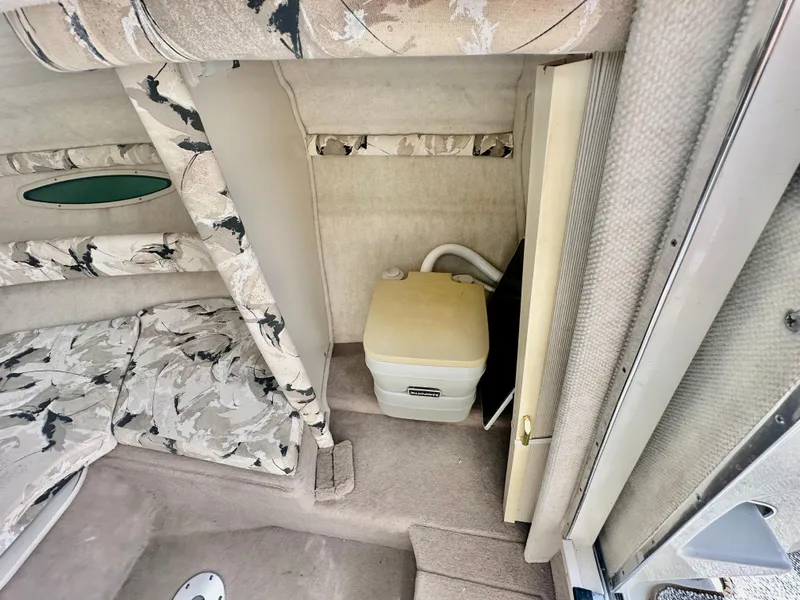Slide: The Image of 2000 Sea Ray 215 Express Cruiser cabin interior with portable toilet and patterned upholstery. - 12