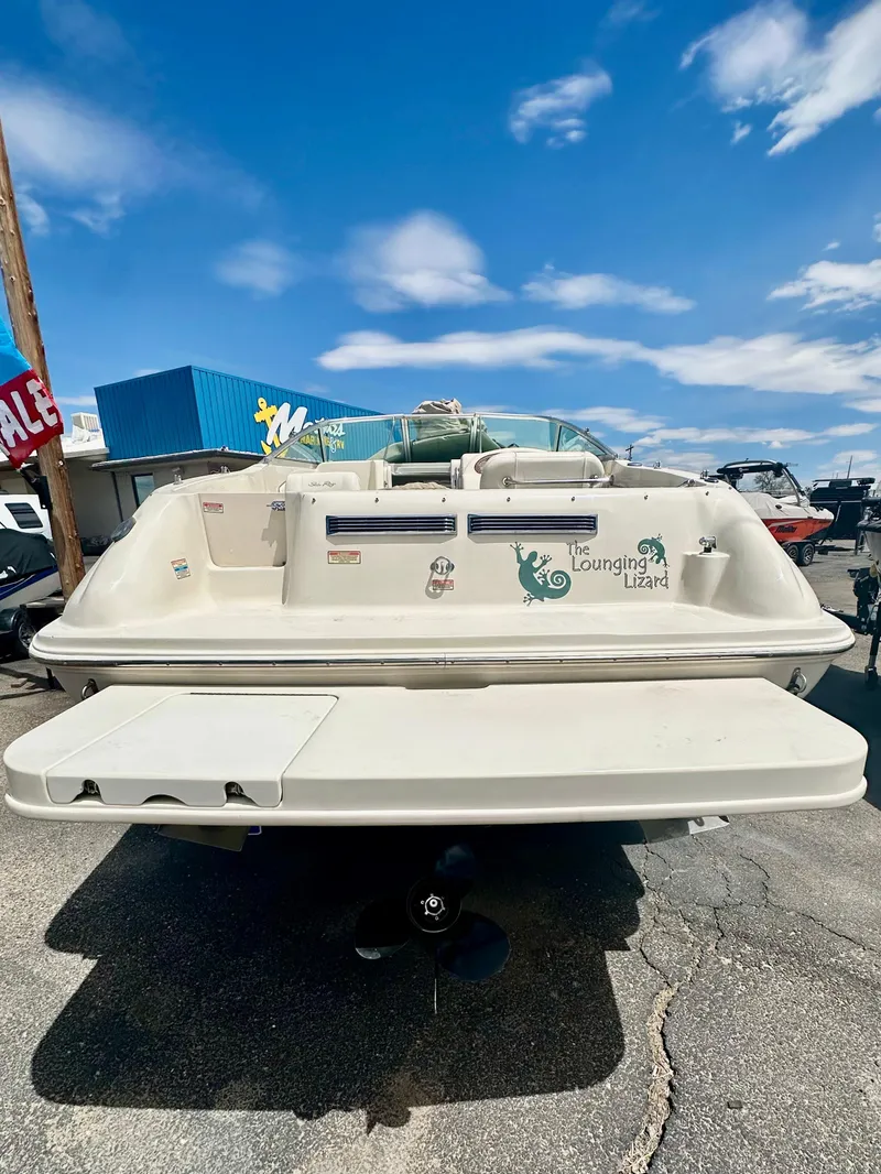 Slide: The Image of 2000 Sea Ray 215 Express Cruiser boat, rear view, parked outdoors under a blue sky. - 3