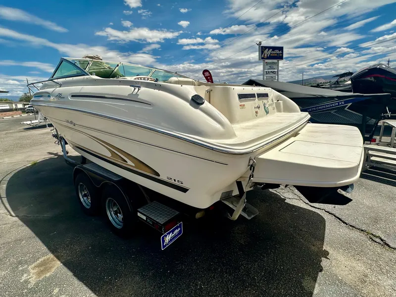 Slide: The Image of 2000 Sea Ray 215 Express Cruiser on trailer under a partly cloudy sky. - 4