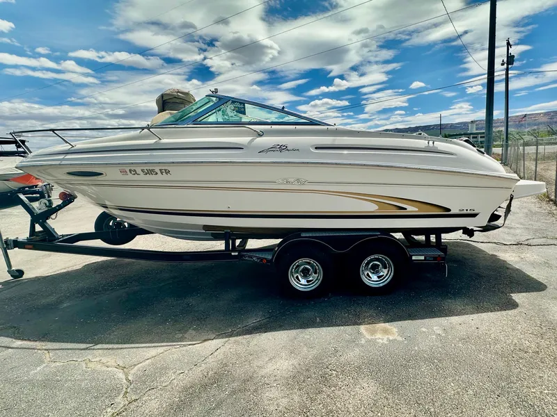 Slide: The Image of 2000 Sea Ray 215 Express Cruiser on trailer under a partly cloudy sky. - 5