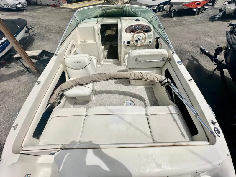 Slide: The Image of 2000 Sea Ray 215 Express Cruiser interior with seating and steering wheel, parked on a lot. - 7