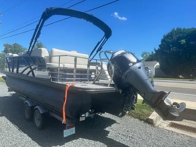 Slide: The Image of 2022 Sylvan Mirage X3 Tri Toon boat on trailer, parked outdoors under clear blue sky. - 2
